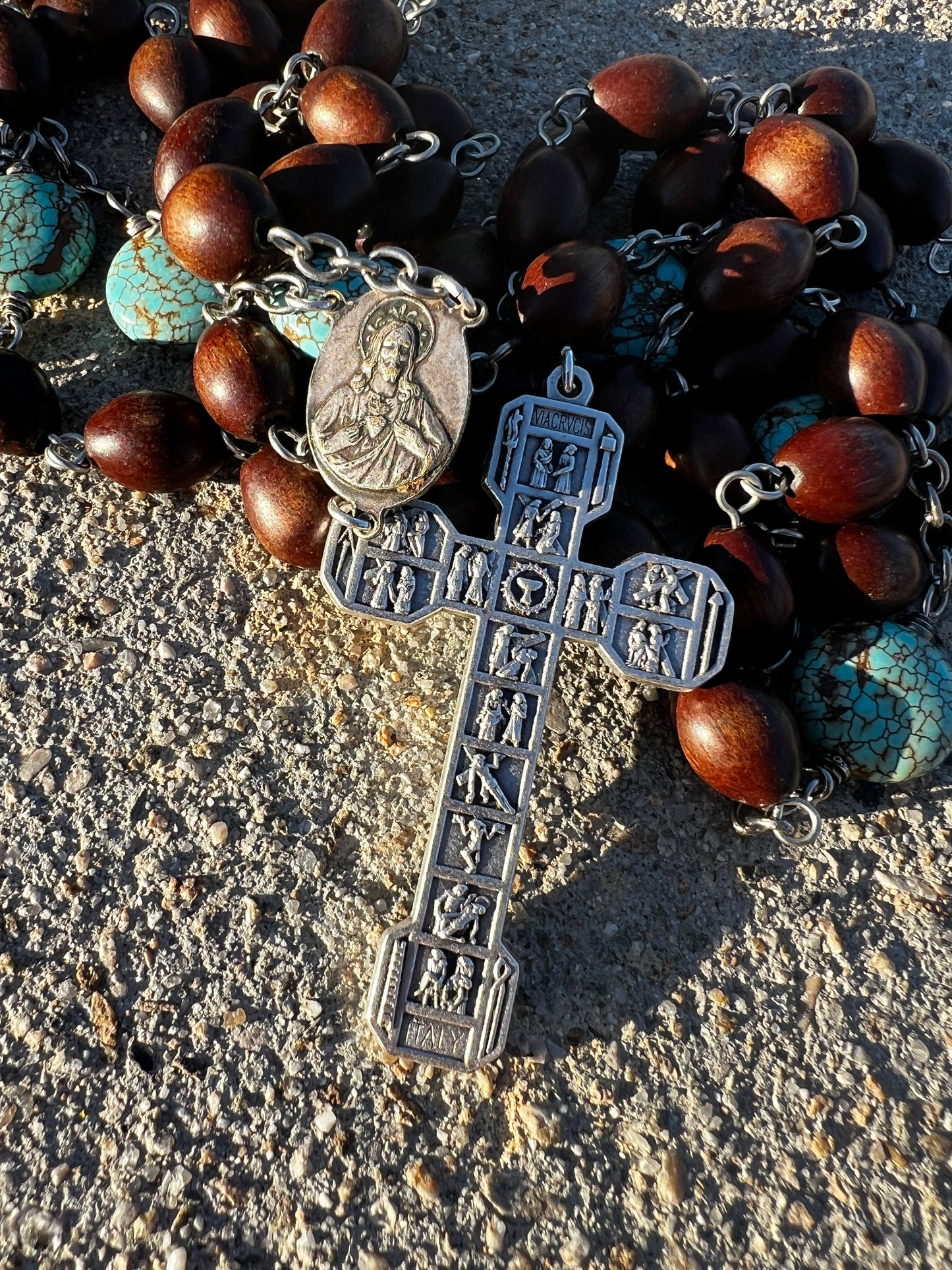 Rosary with brown beads and a silver cross on a textured surface